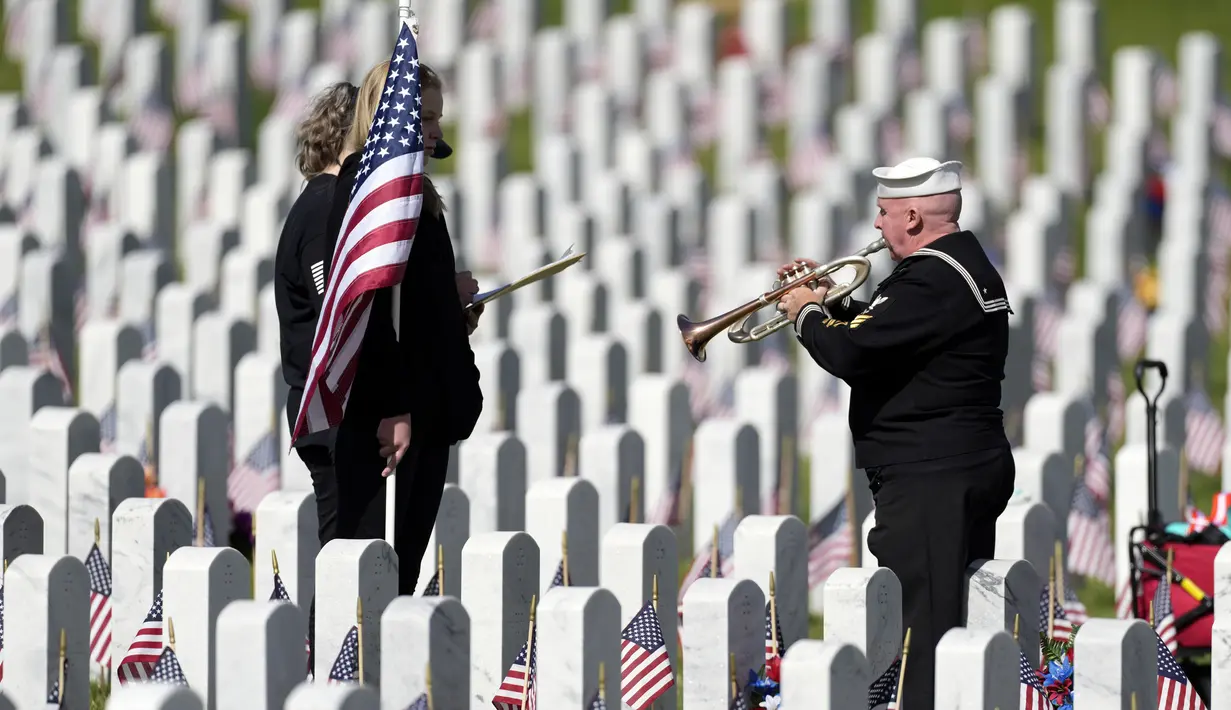 Pensiunan Angkatan Laut Amerika Serikat Yeoman Mark Stallins memainkan Taps untuk keluarga prajurit yang gugur di sebuah kuburan di Pemakaman Nasional Fort Logan, Sheridan, Colorado, Amerika Serikat, 30 Mei 2022. (AP Photo/David Zalubowski)