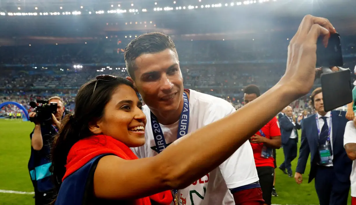 Cristiano Ronaldo berfoto dengan seorang fan seusai menjuarai Piala Eropa 2016 di Stade de France, Saint-Denis, Senin (11/7/2016) dini hari WIB. (Reuters/Michael Dalder)