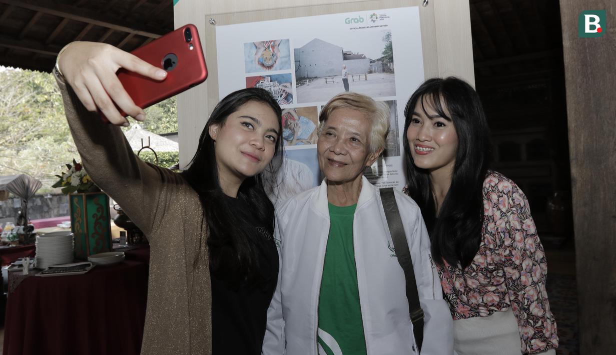 Pengunjung foto bersama legenda bulutangkis, Tati Sumirah, saat pameran foto di Yogyakarta, Rabu (18/7/2018). Pameran foto legenda olahraga Indonesia tersebut sekaligus peluncuran kampanye Grab "Kemenangan itu Dekat". (Bola.com/M Iqbal Ichsan)