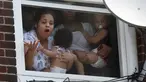 Wanita menggendong bayi menunggu bantuan setelah kebakaran terjadi di dalam gedung apartemen di Hazleton, Pennsylvania (26/7/2019). Pemadam kebakaran kota menggunakan truk menyelamatkan penghuni dari lantai tiga gedung. (Warren Ruda/Hazleton Standard-Speaker via AP)