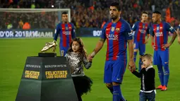 Striker Barcelona, Luis Suarez, didampingi anaknya saat menunjukan Sepatu Emas jelang laga La Liga melawan Granada di Stadion Nou Camp, Spanyol, Sabtu (29/10/2016). Suarez meraih gelar ini usai mencetak 40 gol pada musim lalu. (AFP/Lluis Gene)