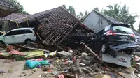 Dua unit mobil tertimbun reruntuhan rumah yang rusak setelah tsunami menerjang kawasan Anyer, Banten, Minggu (23/12). Data sementara jumlah korban dari bencana tsunami di Selat Sunda tercatat 168 orang meninggal dunia. (Liputan6.com/Angga Yuniar)