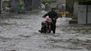 Seorang warga mendorong motornya melintasi jalan yang banjir akibat hujan lebat di Peshawar, Pakistan, Senin, 15 April 2024. (AP Photo/Muhammad Sajjad)