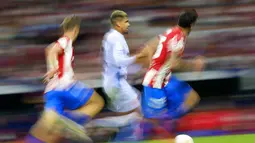 Bek Barcelona, Ronald Araujo (tengah) membawa bola dari kejaran dua pemain Atletico Madrid pada pertandingan lanjutan La Liga Spanyol di Estadio Wanda Metropolitano di Madrid, Minggu (3/10/2021). Atletico Madrid kini berada di urutan kedua klasemen dengan 17 poin. (AP Photo/Manu Fernandez)