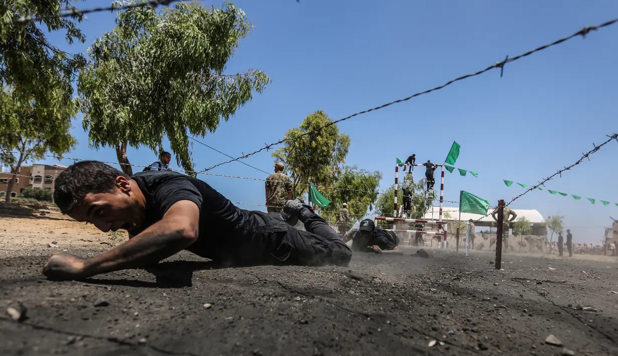 Sejumlah kadet Palestina melewati rintangan kawat berduri saat berlatih fisik dengan militer Hamas, Brigade Ezzedin al-Qassam, di Kota Gaza (20/7/2019). Sejumlah pemuda Palestina direkrut Hamas untuk menjadi bagian anggotanya. (AFP Photo/Mahmud Hams)