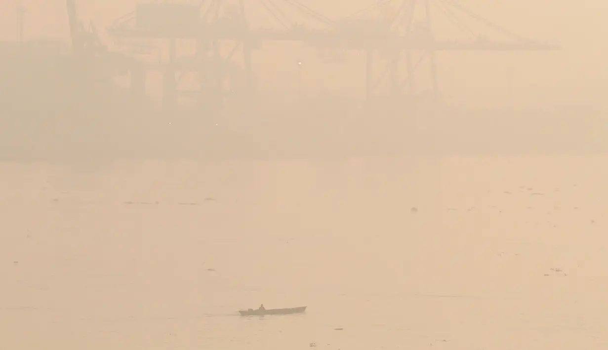 Sebuah perahu melintasi Sungai Musi di tengah kabut asap tebal akibat kebakaran hutan di Palembang, Sumatera Selatan, Kamis (22/10/2026). (AP Photo/Muhammad Hatta)