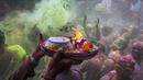 Umat Hindu dengan persembahan berjalan menuju mobil yang membawa patung dewa Krishna selama festival Holi di Kolkata, India, Minggu, 5 Maret 2023. Dalam festival Holi di India, warga saling melempar serbuk warna-warni.(AP Photo/Bikas Das)