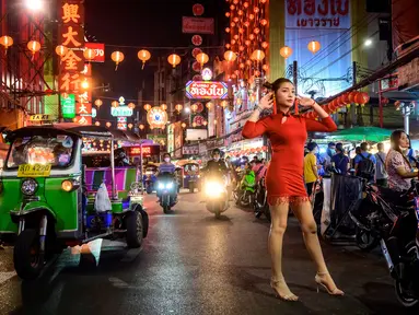 Seorang wanita berpose untuk berfoto di jalan yang didekorasi untuk menyambut Tahun Baru Imlek yang akan datang di Chinatown Bangkok (9/2/2021). Perayaan Tahun Baru Imlek 2021 di Chinatown Yaowarat Bangkok secara resmi dibatalkan menurut Administrator Metropolitan Bangkok. (AFP/ Mladen Antonov)
