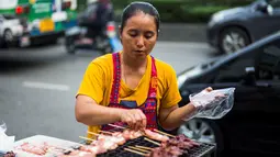 Seorang wanita memasak sate di gerobaknya di samping jalan di Bangkok, Thailand (20/9). Kota Bangkok, terkenal sebagai salah satu street food capital alias kota yang identik dengan makanan pinggir jalan. (AFP Photo/Jewel Samad)