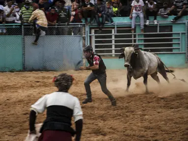 Badut rodeo mencoba mengalihkan perhatian banteng setelah penunggangnya terjatuh saat bertanding di pameran rodeo Boyeros Cattlemen di Pameran Pertanian Internasional Fiagrop 2022 di Havana, Kuba (8/4/2022). Rodeo di Kuba adalah tradisi yang berusia lebih dari dua abad. (AP Photo/Ramon Espinosa)