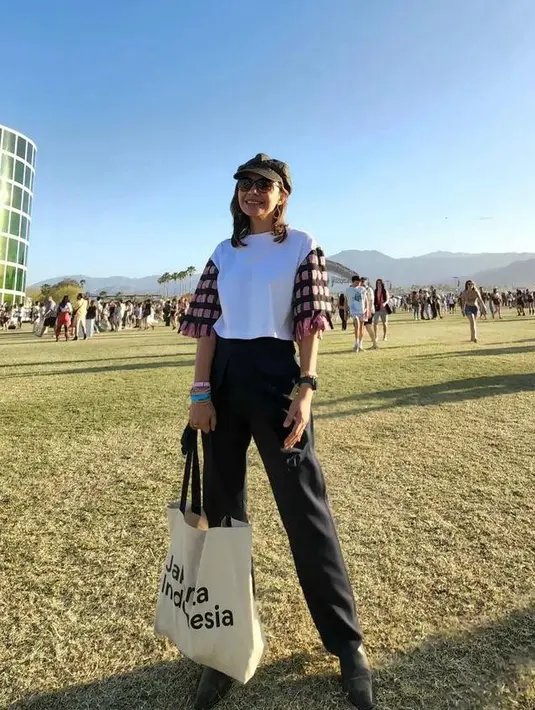 Gaya kasual Najwa Shihab saat nonton konser Coachella 2022 juga bisa disontek.  Padukan blouse dengan sedikit aksen dengan high waisted pants. Maksimalkan pada aksesori, seperti breton hat dan totebag. (Instagram/najwashihab).