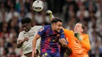Kiper Barcelona, Wojciech Szczesny, meninju bola melewati Aurelien Tchouameni dari Real Madrid dan Eric Garcia dari Barcelona dalam pertandingan La Liga di Santiago Bernabeu, Minggu, 26 Oktober 2025. (AP Photo/Bernat Armangue)