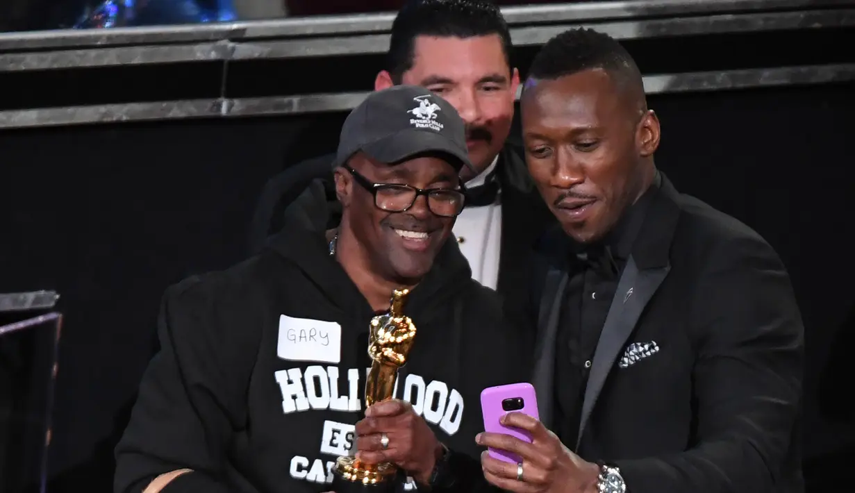 Turis berfoto bersama aktor pendukung terbaik Piala Oscar 2017, Mahershala Ali, selama Academy Awards ke-89, di California, Minggu (26/2). Oscar tahun ini mendapat kejutan dengan kedatangan para turis yang diajak masuk oleh Jimmy Kimmel (Mark RALSTON/AFP)