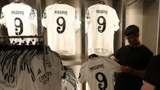 Seorang pria memegang jersey pemain sepak bola Prancis, Kylian Mbappe yang baru saja diluncurkan di toko resmi Real Madrid di stadion Santiago Bernabeu, Madrid, pada 11 Juli 2024. (Pierre-Philippe MARCOU/AFP)