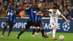 Pemain Paris Saint-Germain Lionel Messi (kanan) berebut bola dengan pemain Club Brugge Eder Alvarez Balanta pada pertandingan Grup A Liga Champions di Stadion Jan Breydel, Bruges, Belgia, Rabu (15/9/2021). Pertandingan berakhir imbang 1-1. (JOHN THYS/AFP)