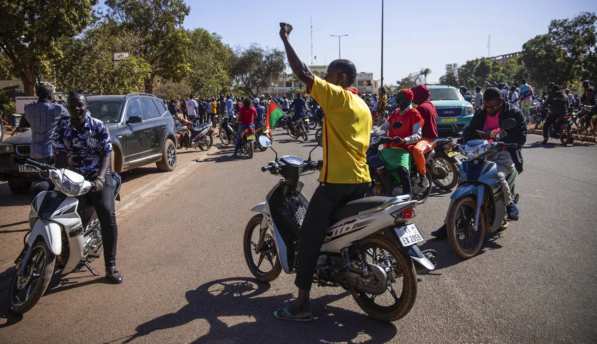 Orang-orang bersorak mendukung tentara kudeta di dekat stasiun televisi nasional di Ouagadougou, Senin (24/1/2022). Atas penggulingan ini, pihak militer Burkina Faso dilaporkan menangguhkan konstitusi, membubarkan pemerintah dan majelis nasional, serta menutup perbatasan negara. (AP/Sophie Garcia)