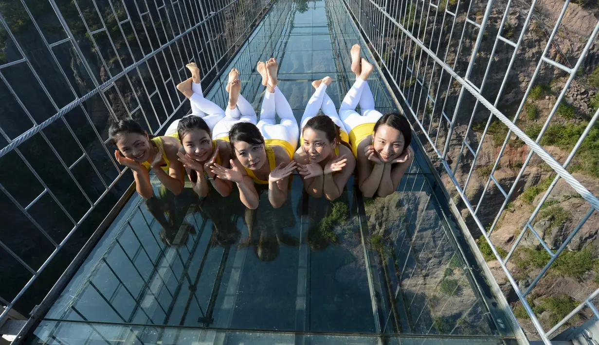 Para perempuan berpose saat melakukan yoga di jembatan kaca di Taman Nasional Shiniuzhai di Pingjiang, provinsi Hunan, China, Kamis (5/11). Latihan di atas ketinggian 180 meter ini untuk mempromosikan hidup sehat dengan beryoga. (REUTERS/China Daily)