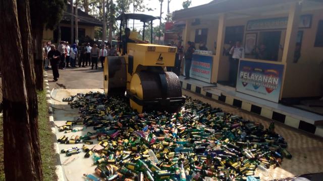Sebuah alat berat, tengah memusnahkan ribuan botol miras berbagai jenis hasil razia menjelang natal dan tahun baru di Garut