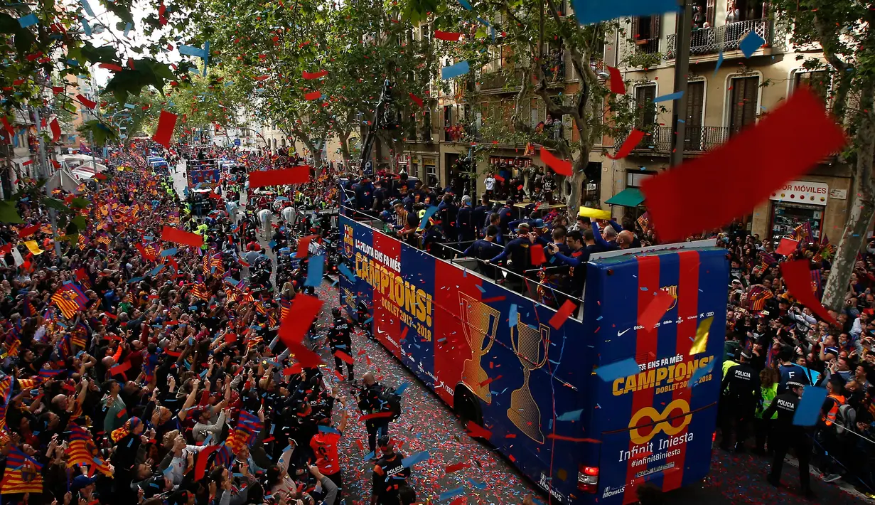 Para warga dan penggemar menyambut pemain Barcelona yang berada di atas bus saat parede untuk merayakan juara La Liga Spanyol di Barcelona (30/4). (AP/Manu Fernandez)