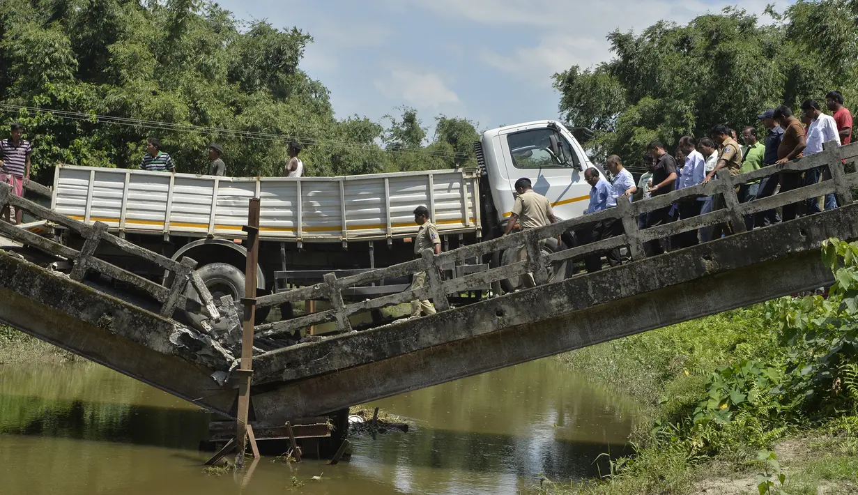 Petugas penyelamat dan penduduk desa India berkumpul di dekat jembatan yang runtuh di desa Phasidewa dekat perbatasan India-Bangladesh di pinggiran Siliguri di negara bagian India, Bengal Barat (7/9). (AFP Photo/Diptendu Dutta)