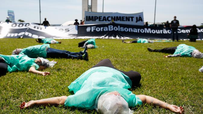 Demonstran berbaring di atas tanah saat memprotes Presiden Brasil Jair Bolsonaro dan penanganannya terhadap pandemi virus corona di Brasilia, pada Minggu (31/1/2021). Di antara mereka bahkan banyak yang menuntut pengunduran diri atau pemakzulan Presiden Brasil Jair Bolsonaro. (Sergio LIMA/AFP)