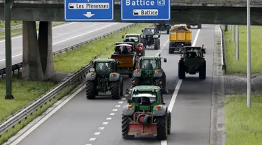 Peternak sapi perah menaiki traktor mereka di jalan tol atau jalan bebas hambatan saat melakukan aksi protes di Battice, Belgia, Kamis (30/7/2015). Aksi protes tersebut berkaitan dengan rendahnya harga jual susu. (REUTERS/Francois Lenoir)