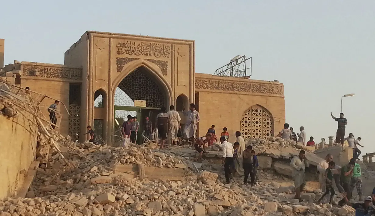 Para warga terlihat berjalan melalui puing-puing makam Nabi Yunus setelah dihancurkan dalam serangan bom oleh militan Negara Islam Irak dan Suriah (ISIS), (24/7/14) (REUTERS/Stringer)