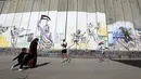 Peserta berlari menyusuri tembok pemisah Israel selama Right to Movement Maraton di kota Bethlehem, Palestina, Jumat (1/4). Tembok ini menjadi sarana bagi seniman jalanan untuk menuangkan keahliannya. (REUTERS / Ammar Awad)