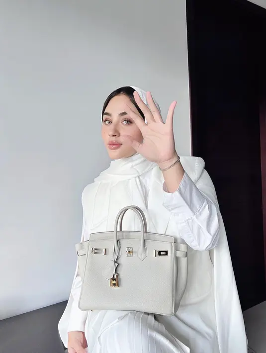 Tampil serba putih, Margin mengenakan pashmina yang menyisakan sebagian rambutnya sambil tenteng tas mewah. Penampilan Margin satu ini dipuji bak barbie hidup.  @marginw.