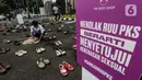 Pegiat komnas perempuan merapikan sepatu saat aksi diam 500 Langkah Awal Sahkan RUU PKS di depan gedung DPR, Jakarta, Rabu (25/11/2020). Dalam aksinya mereka menyusun sepatu sebagai simbol "semua peduli, semua terlindungi, stop sexual violence". (Liputan6.com/Johan Tallo)