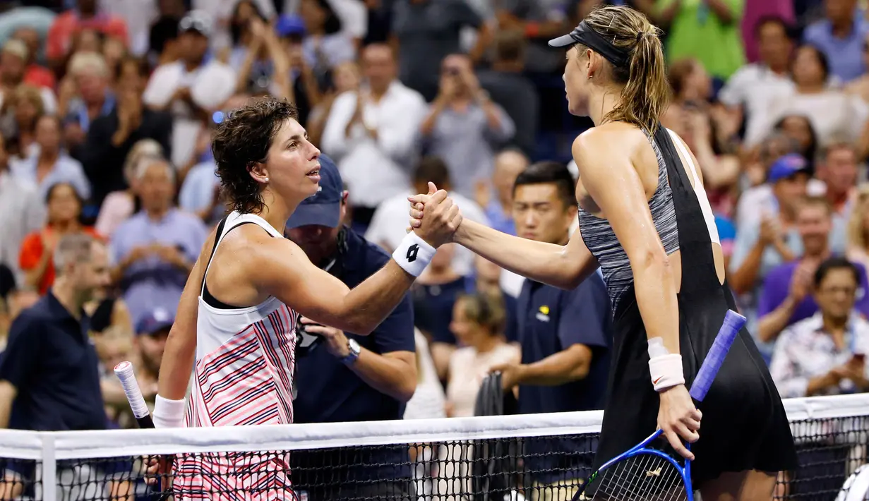Petenis Rusia, Maria Sharapova bersalaman dengan Carla Suarez Navarro dari Spanyol usai pertandingan 16 besar AS Terbuka 2018 di USTA Billie Jean King National Tennis Center, New York, (3/9). Sharapova kalah dua set 6-4, 6-3. (AP Photo/Jason DeCrow)