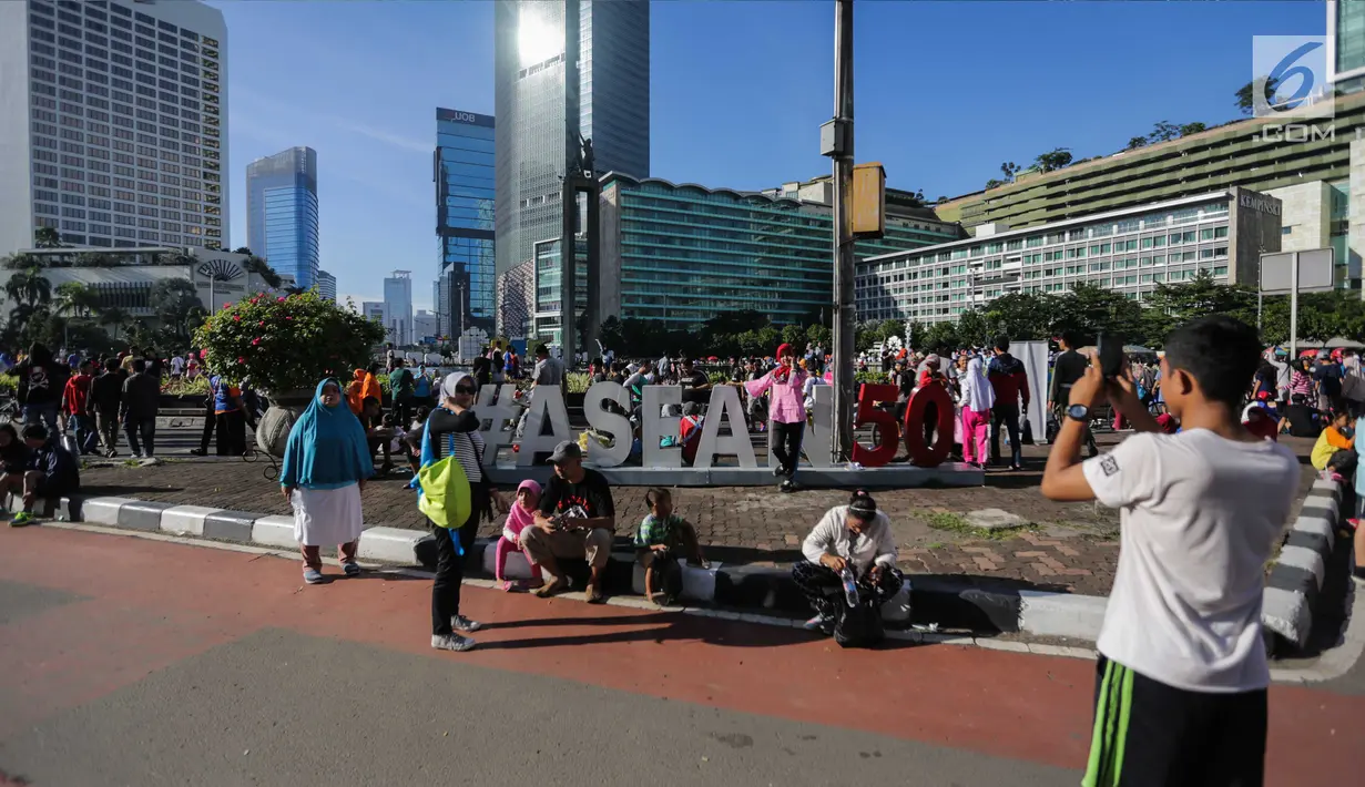 Warga berfoto saat berlangsungnya Hari Bebas Kendaraan Bermotor (HBKB), Jakarta, Minggu (24/12). Pemprov DKI Jakarta tetap memberlakukan HBKB saat libur panjang Natal 2017 dan tahun baru 2018. (Liputan6.com/Faizal Fanani)