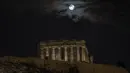 Bulan purnama terakhir tahun ini yang dikenal sebagai bulan dingin muncul di atas kuil kuno Parthenon saat hari mendung, di Athena, Yunani, Rabu (7/12/2022). Bulan purnama Desember sendiri dikenal sebagai Cold Moon atau Bulan Dingin. (AP Photo/Petros Giannakouris)