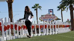 Sherri Camperchioli menata nisan untuk menghormati korban tewas penembakan massal yang terjadi dekat Kasino Mandalay Bay di Las Vegas, Jumat (6/10). Sebanyak 58 nisan kayu berbentuk salib itu ditambahkan ornamen hati berwarna merah. (AP/Gregory Bull)