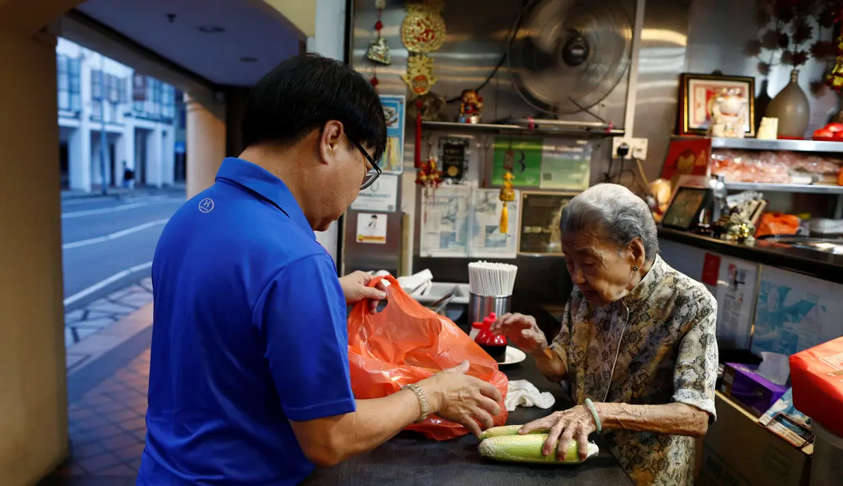 Nenek Leong Yuet Meng (90) dan putranya Michael Tang (66) bersiap untuk membuka warungya di Singapura (22/2). Leong Yuet Meng masih menjalankan usaha warung mie pangsit, meski berusia sudah menginjak 90 tahun. (Reuters/Edgar Su)