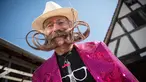 Salah satu peserta memperlihatkan janggut miliknya yang dibentuk menyerupai Menara Eiffel (kanan) sebelum mengikuti kompetisi janggut dan kumis di Ecomusee d'Alsace, Ungersheim, Prancis, 30 Maret 2017. (AFP PHOTO/SEBASTIEN BOZON)