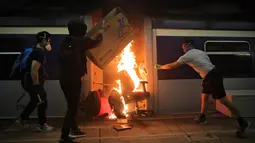 Sejumlah pelajar membakar kereta yang terparkir di Stasiun MTR Chinese University, Hong Kong, Rabu (13/11/2019). Gerakan antipemerintah Hong Kong yang telah berlangsung selama lima bulan bertindak semakin keras. (AP Photo/Kin Cheung)