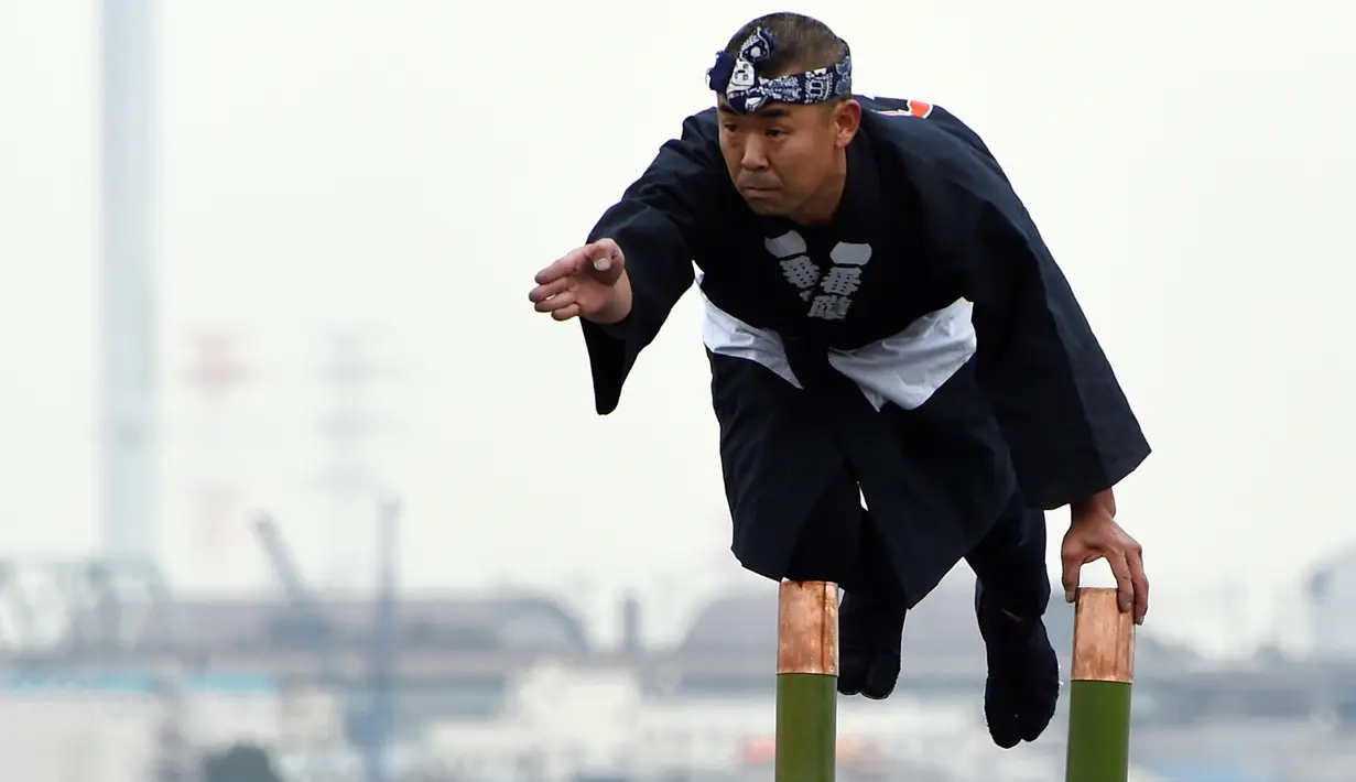 Seorang pemadam kebakaran yang berpakaian tradisonal menunjukan keahliannya menyeimbangkan tubuh di atas puncak bambu saat perayaan Tahun Baru di Tokyo, Jepang, Jumat (6/1). Atraksi ini dipersembahkan untuk perayaan Tahun Baru. (Toshifumi KITAMURA/AFP)