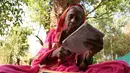 Nenek Sulochona Kedar (68) membaca buku selama mengikuti kegiatan di Sekolah Aajibaichi Shaala, Desa Fangane, India, pada 1 Maret 2017. Sama seperti sekolah pada umumnya, Sekolah ini memiliki aturan dalam berpakaian. (AFP Photo / Indranil Mukherjee)