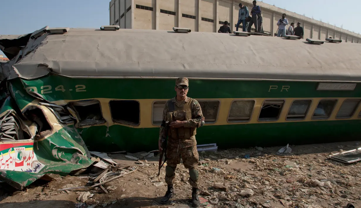 Petugas keamanan Pakistan berdiri berjaga di depan bangkai kereta setelah terjadi kecelakaan di Karachi, Pakistan, Kamis (3/11). (AP Photo/Shakil Adil)