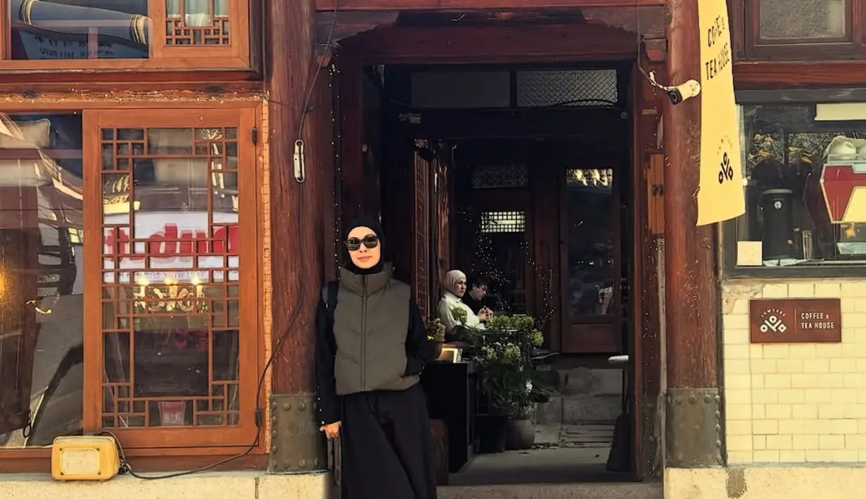 Ratna Galih mengenakan padding vest jaket abu-abu dipadukan inner dan rok hitam, senada dengan kerudungnya. Ia mengenakan sepatu putih Onitsuka dan kacamata hitamnya. [@ratnagalih]