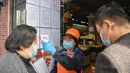 Pekerja memeriksa kode QR kesehatan dan suhu tubuh pelanggan di toko bahan makanan segar di Distrik Xiling, Kota Yichang, Provinsi Hubei, China, Jumat (20/3/2020). Warga kini dapat memasuki dan meninggalkan area tempat tinggal mereka dengan kode QR kesehatan yang memenuhi syarat. (Xinhua/Cheng Min)