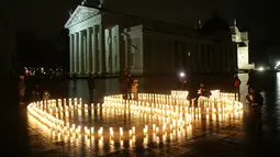 Pengunjung menyalakan lilin untuk memperingati Earth Hour Internasional di Katedral Vilnius di Lithuania (25/3). (AFP/Petras Malukas)