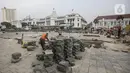 Pekerja menyelesaikan proyek revitalisasi di depan Stasiun Jakarta Kota, kawasan Kota Tua, Jakarta, Sabtu (23/7/2022). Pemprov DKI Jakarta menyatakan program revitalisasi di kawasan Kota Tua salah satunya bertujuan untuk meningkatkan aksesibilitas dengan mengintegrasikan beragam moda transportasi seperti kereta api, MRT, Transjakarta hingga angkutan perkotaan. (Liputan6.com/Faizal Fanani)