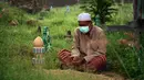 Seorang pria berdoa di sebelah makam kerabat saat perayaan Hari Raya Idul Adha di sebuah pemakaman di Provinsi Narathiwat, Thailand, Rabu (21/7/2021). Setiap Idul Adha atau hari besar Islam lainnya, sebagian warga banyak mendatangi kuburan untuk mendoakan keluarganya. (Madaree TOHLALA/AFP)