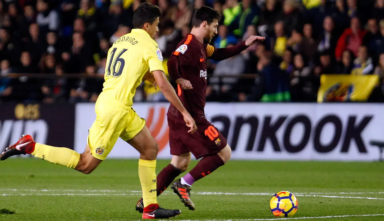 Pemain Barcelona, Lionel Messi berebut bola dengan pemain Villarreal, Rodrigo Hernandez pada jornada ke-15 La Liga di Stadion Ceramica, Minggu (10/12). Barcelona menang 2-0 usai Villarreal bermain dengan sepuluh orang di babak kedua. (AP/Alberto Saiz)