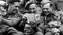 Sambil bercanda, beberapa tentara Inggris melihat dan membaca buku panduan wisata tentang Perancis disebuah kapal pendarat, (6/6/1944). (AFP PHOTO)