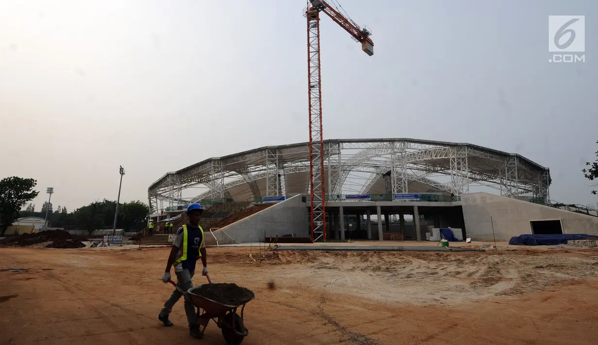 Pekerja melintas di depan pembangunan stadion balap sepeda atau velodrom di Rawamangun, Jakarta, Jumat (3/11). Pembangunan stadion bertaraf internasional ini sudah mencapai 68 persen dan ditarget selesai, Juni 2018. (Liputan6.com/Helmi Fithriansyah)