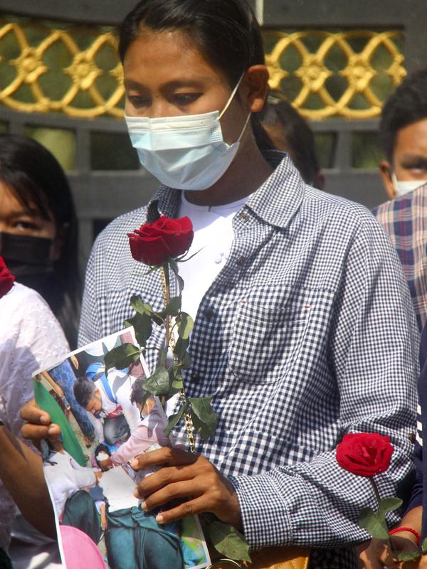 Seorang wanita mempersembahkan bunga mawar sebagai penghormatan kepada seorang guru yang tewas dalam protes kudeta militer di Yangon, Myanmar, Senin (1/3/2021). Para guru mencoba berkumpul lebih awal, tetapi polisi melemparkan granat kejut dan menyerbu untuk membubarkan protes. (AP Photo)