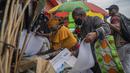 Pasangan bertopeng memilah barang di pasar outdoor dekat pangkalan taksi Baragwanath di Soweto, Afrika Selatan, Kamis (2/12/2021). Afrika Selatan mempercepat kampanye vaksinasi untuk memerangi lonjakan pesat kasus Covid-19 usai mendeteksi varian Omicron pekan lalu. (AP Photo/Jerome Delay)